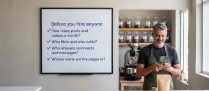 Coffee roaster in Little River checking his phone next to a whiteboard: before you hire anyone, ask how many posts and videos a month, who films and edits, who answers comments and messages, and whose name the pages are in.